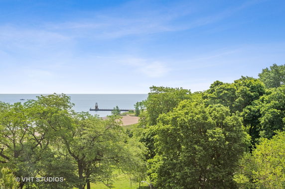 Panoramic view of a coastline with trees and a pier extending into the water.