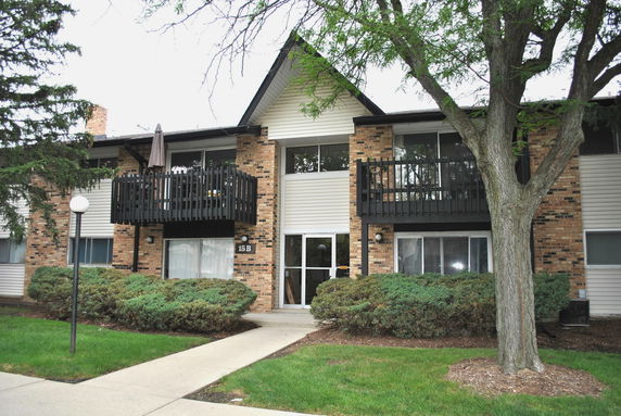 Front view of a two-story building with brick and siding exterior and balconies.