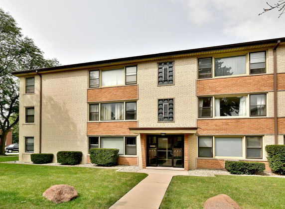 Front view of a three-story residential building with large windows and a central entrance.