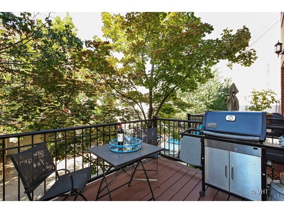 Outdoor patio with a grill and seating area overlooking trees.
