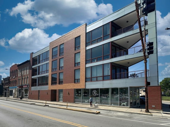 Front view of a modern multi-story building with large windows and brick facade.