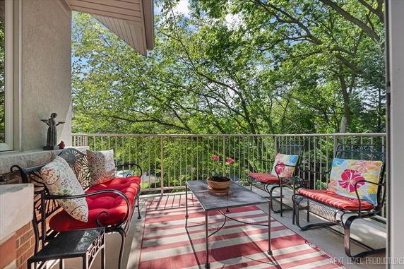 View from a balcony with chairs and plants overlooking trees.