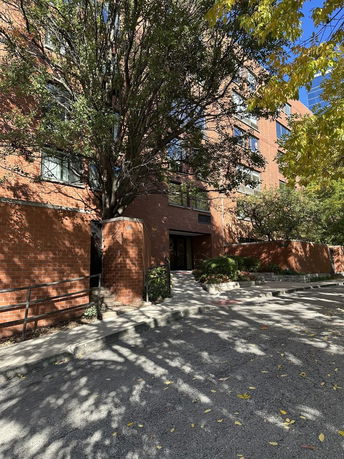 Front view of a multi-story brick apartment building with trees nearby.