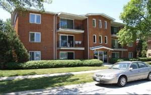 Front view of a three-story brick apartment building with balconies.