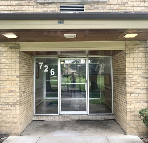 Front view of a brick building entrance with glass doors.