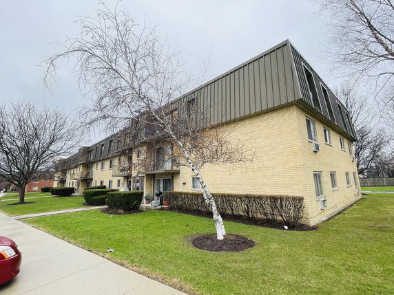 Front view of a multi-story brick apartment building with a sloped roof.