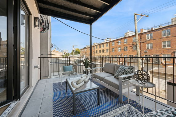 Outdoor balcony view from a building showing nearby brick buildings and utility poles.