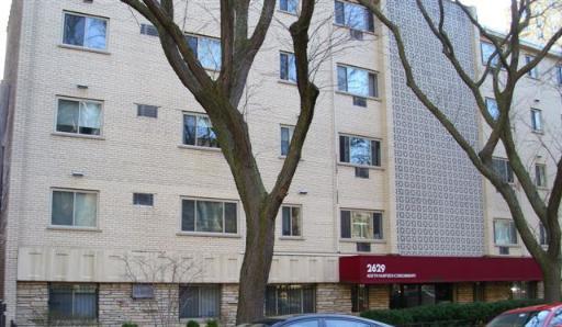 Front view of a multi-story residential building with red awning.