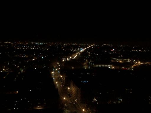 Nighttime panoramic view of a city, showing streets illuminated by lights.