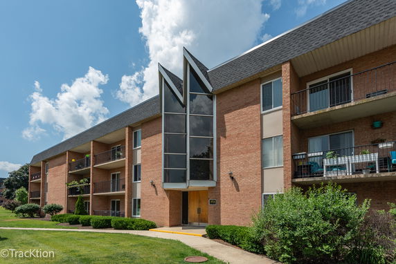Front view of a multi-story brick apartment building with balconies.