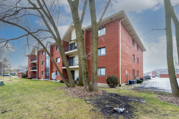 Front view of a multi-story brick apartment building with balconies.