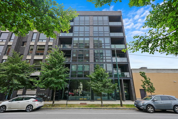 Front view of a multi-story apartment building with glass balconies.