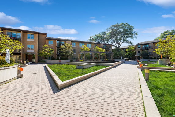 Front view of a three-story residential building complex with walkways and greenery.