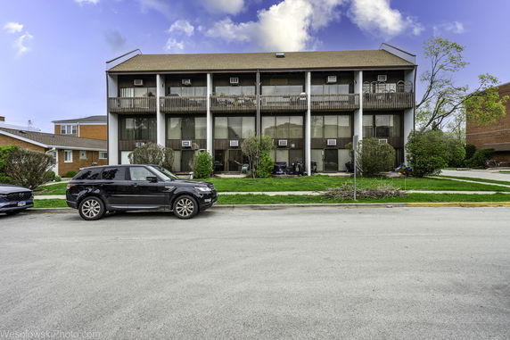 Front view of a three-story building with balconies and large windows.