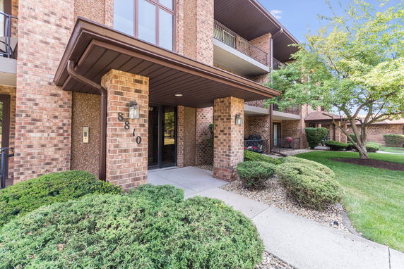 Front view of a brick apartment building entrance with balconies.