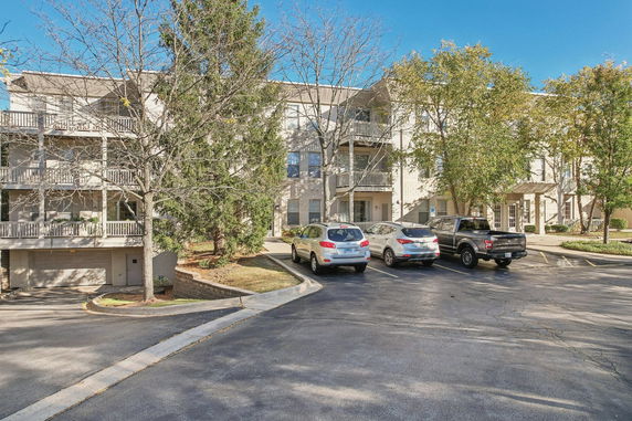 Front view of a multi-story apartment building with balconies and parking area.