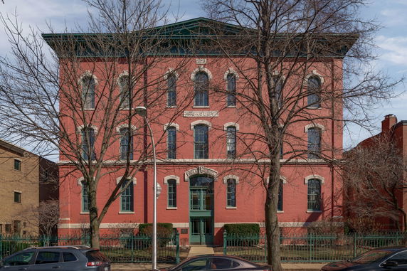 Front view of a red brick multi-story building with arched windows.