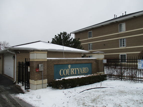 Front view of a multi-story building with a courtyard sign.