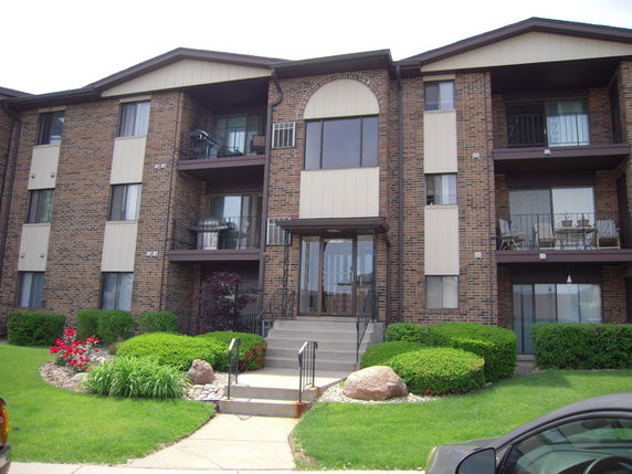 Front view of a multi-story apartment building with brick exterior and balconies.