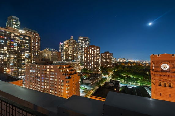 Panoramic view of city skyline at night with illuminated buildings.