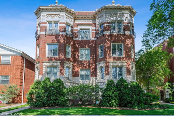 Front view of a multi-story brick building with decorative elements and balconies.