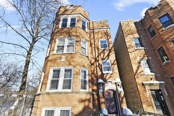 Front view of a multi-story brick apartment building with bay windows.