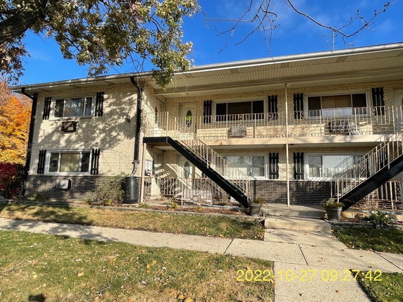 Front view of a two-story residential building with balconies and external staircases.