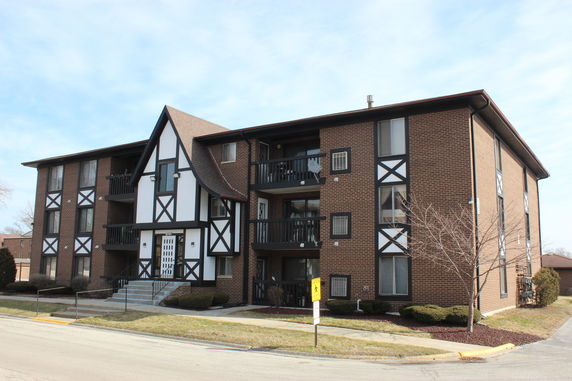 Front view of a three-story apartment building with brick and decorative timber details.