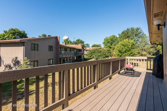 View from a balcony overlooking adjacent residential buildings and greenery.