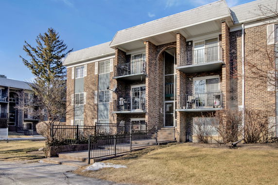 Front view of a multi-story brick apartment building with balconies.