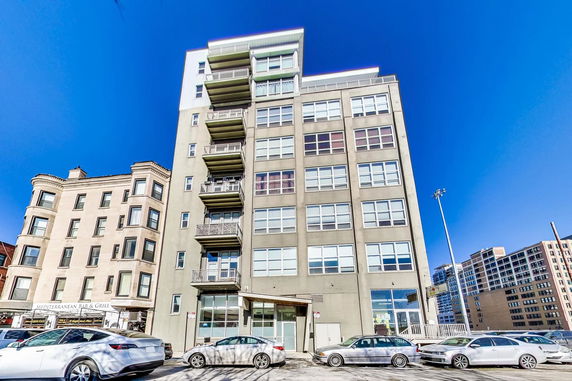 Front view of a multi-story building with balconies and large windows.