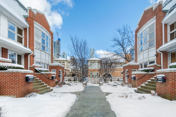 Front view of brick buildings with large windows and steps, surrounded by snow.