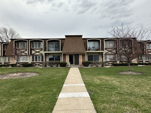 Front view of a multi-story residential building with distinct window designs and a central entrance.