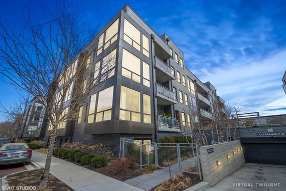 Front view of a modern multi-story apartment building with large windows and balconies.