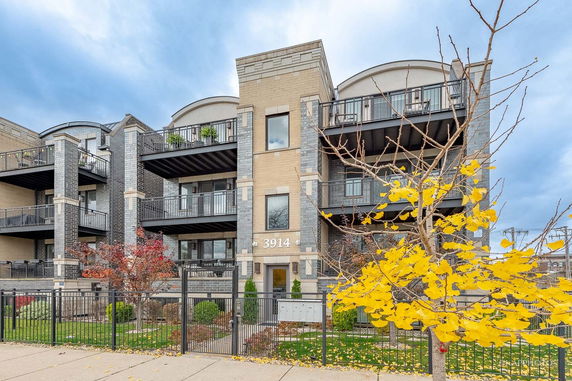 Front view of a multi-story apartment building with balconies and a gated entrance.