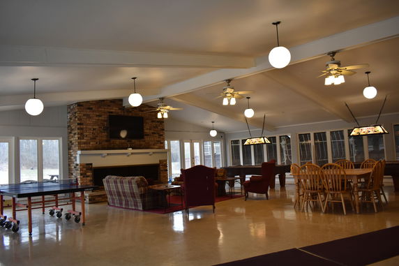 Interior of a recreational room with a ping pong table, dining area, and seating.