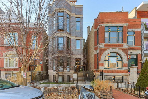 Front view of a multi-story townhouse with a modern design adjacent to other residential buildings.