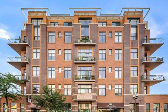 Front view of a multi-story brick apartment building with balconies.
