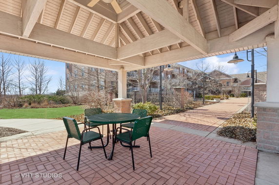 Outdoor seating area with a roof structure and view of nearby buildings.
