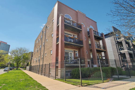 Front view of a multi-story apartment building with balconies and a brick exterior.