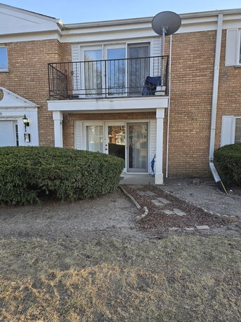 Front view of a two-story brick building with balconies and sliding glass doors.
