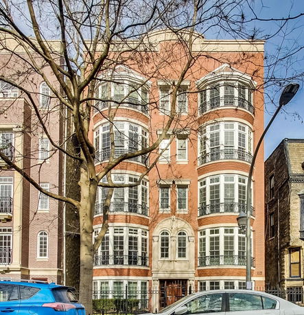 Front view of a multi-story brick building with large windows and balconies.