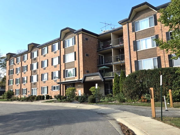 Front view of a four-story brick apartment building with multiple balconies.