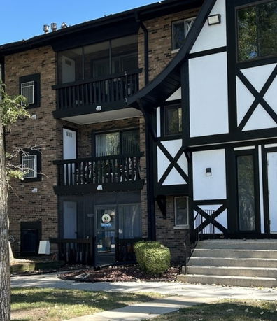 Front view of a multi-story apartment building with Tudor-style design elements.