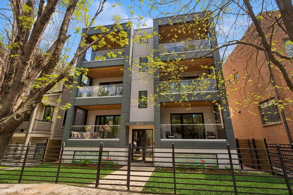 Front view of a modern multi-story apartment building with balconies and a glass facade.