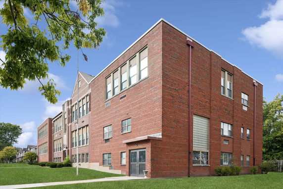 Front view of a large brick building with multiple levels and large windows.