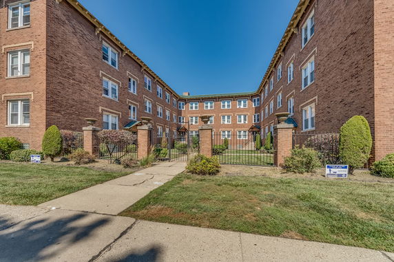 Front view of a U-shaped brick residential building with a gated entrance.