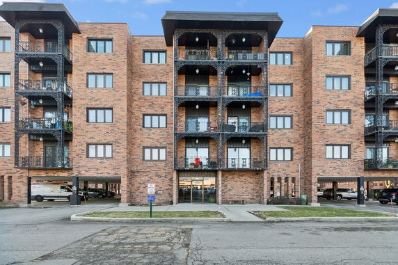 Front view of a multi-story brick apartment building with balconies.