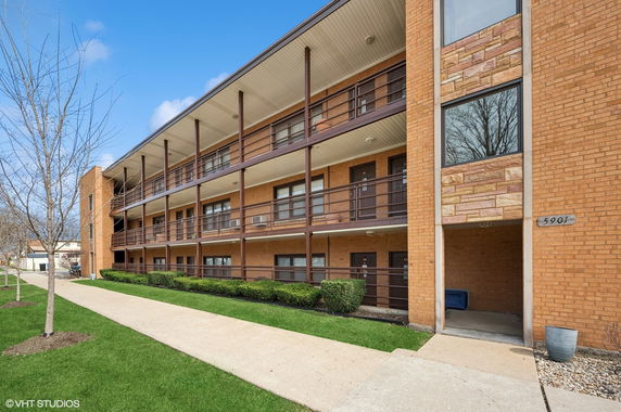 Front view of a multi-story apartment building with balconies and a brick facade.