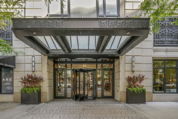 Front view of a building with a glass canopy and revolving door entrance.